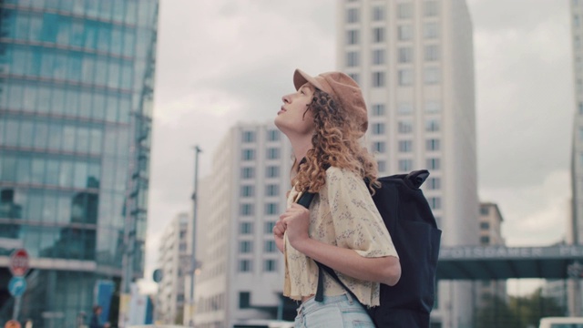 一个背着背包戴着帽子的年轻女子在柏林市中心仰望视频素材