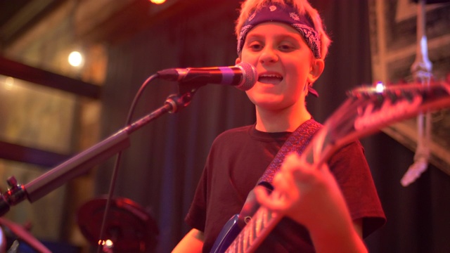 一个音乐家摇滚明星青少年在一个摇滚乐队的舞台上弹吉他。——慢动作视频下载