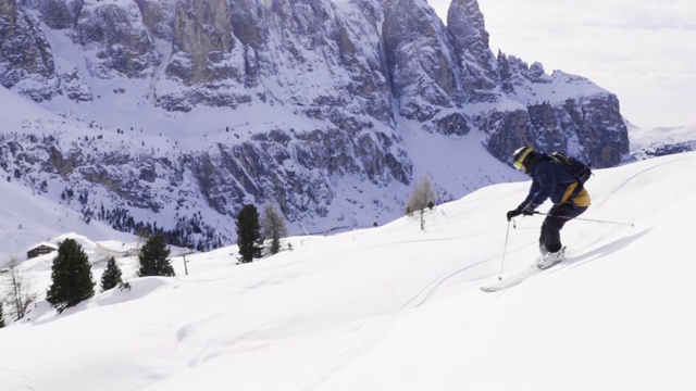 跟随特写:快乐的滑雪者有乐趣滑雪在一个阳光明媚的冬天在雪山的backcountry。极速免费滑雪滑雪者在意大利白云石山滑雪胜地的雪道上骑着新鲜的粉末雪视频素材