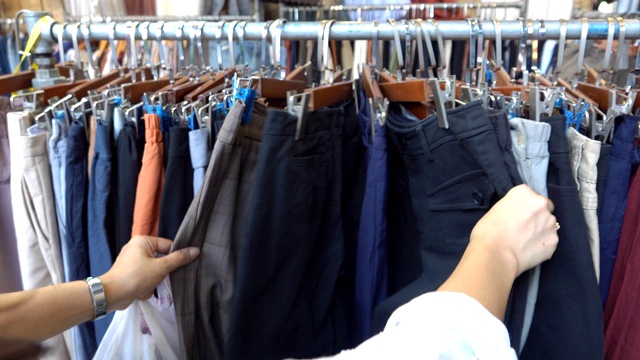 女人在店里挑选挂在衣架上的牛仔裤视频下载