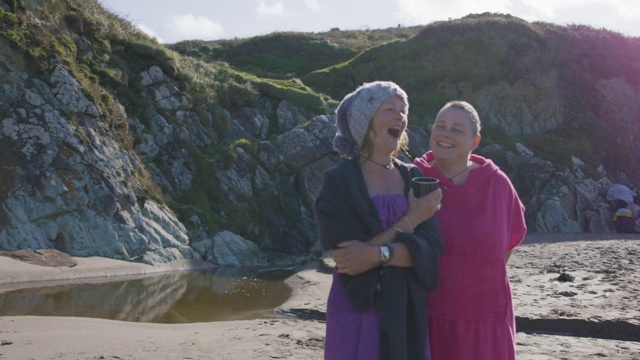 两个女人朋友在海边游泳后，在空荡荡的沙滩上谈笑风生。视频素材