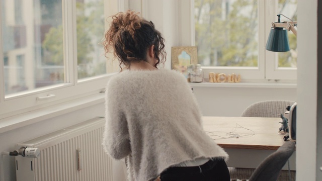 柏林的一个年轻女子，喝着咖啡，坐在家里，拿着笔记本电脑视频下载
