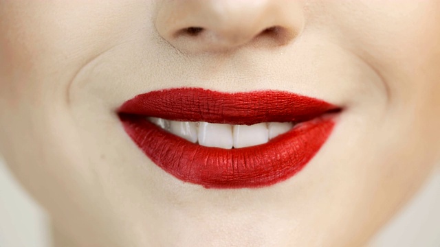 红色的口红和洁白的牙齿。女人高兴地笑着。视频下载