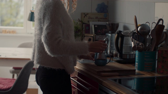 柏林，一名年轻女子把浓缩咖啡倒进马克杯里，在家里闻咖啡味视频素材