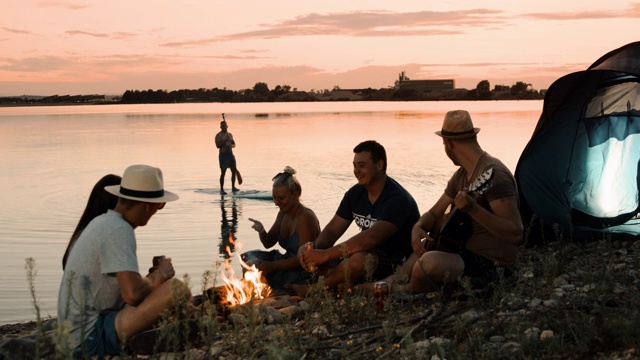 黄昏时分在湖边露营的一群年轻人视频素材