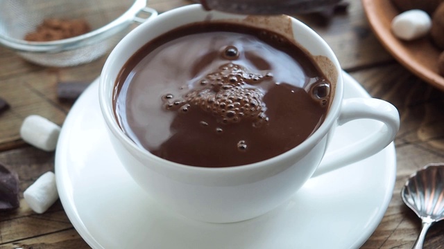 热巧克力倒进一个白色的陶瓷杯里。舒适的冬天的概念。喝可可、和风和巧克力视频下载