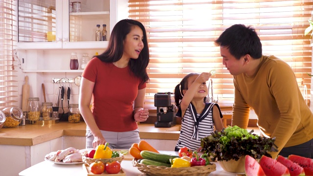快乐的年轻亚洲家庭准备和烹饪健康的食物在厨房，家庭放松和花时间在一起在家里视频下载