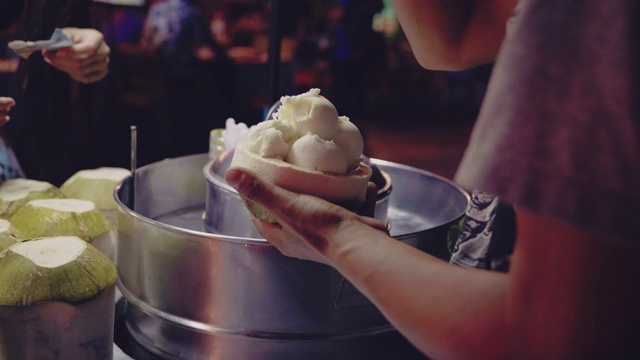 亚洲女游客在曼谷跳蚤市场享用椰子冰淇淋视频素材