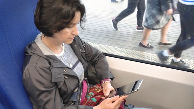 一个白人女人坐在火车上坐在窗边看着平板电脑屏幕视频素材