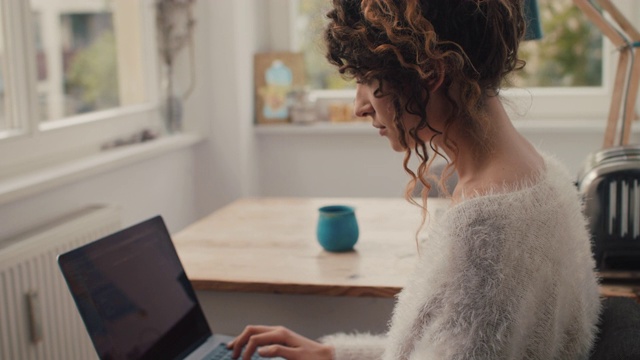 柏林一名年轻女子在家里用笔记本电脑打字视频素材
