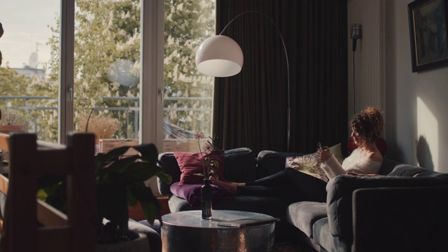 柏林一名年轻女子在家里的沙发上拿着智能手机视频素材