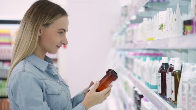 购物-年轻女子拿着一瓶洗发水在超市视频素材