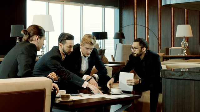 四名商人在现代餐厅的商务会议上讨论交易。4 k视频素材