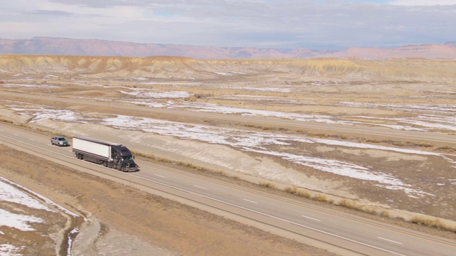 无人机:在一架大卡车上方飞行，拖着一个货运集装箱穿越寒冷的沙漠视频素材