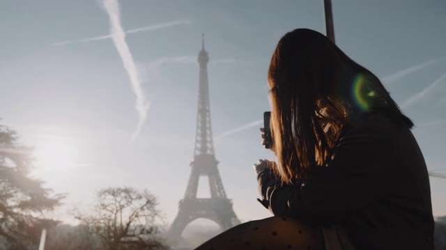 快乐的年轻女游客正在用智能手机拍摄巴黎埃菲尔铁塔的日落全景。视频素材