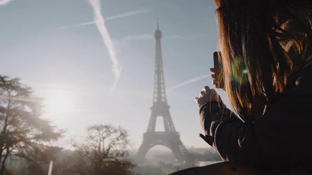 开心兴奋的当地博主女人拍摄了史诗般的日落巴黎艾菲尔铁塔的天空全景与手机慢动作。视频素材