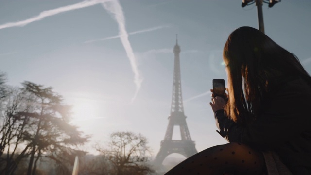 快乐的年轻女博主拍摄日落巴黎埃菲尔铁塔全景与手机度假慢动作。视频素材