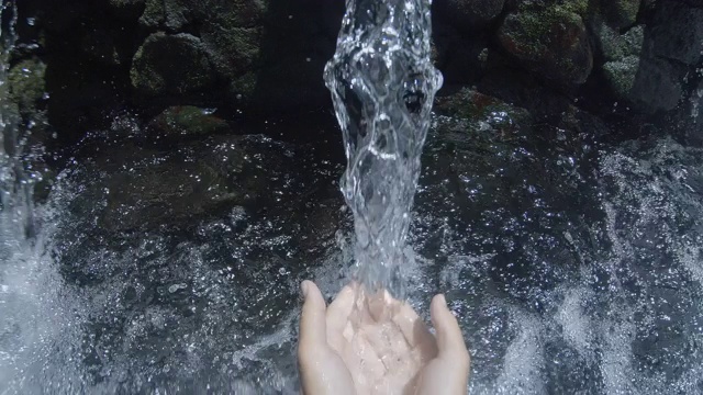 印度尼西亚巴厘岛，一名男子在热带瀑布中洗手。视频下载