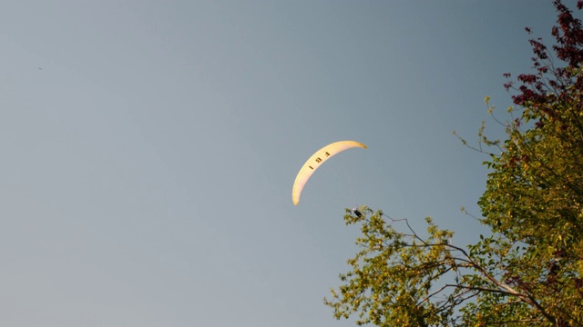 黄色孤立的滑翔伞在阿尔卑斯山脉上方灰色多云的天空中飞行。男运动员正在滑翔伞。视频素材