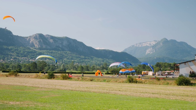 在阿尔卑斯山的滑翔伞站上降落伞课。运动员们从滑翔伞上起飞，迎着蓝天和高山视频素材