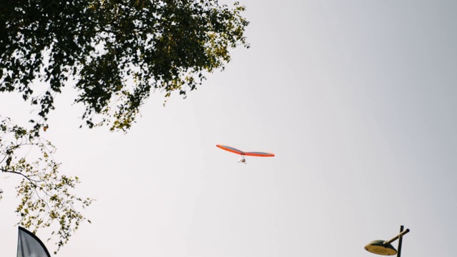橙色孤立悬挂滑翔机在灰色多云的天空中飞行。在阿尔卑斯山上滑翔机飞行课视频素材