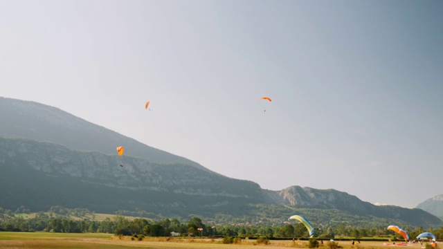 一群人在以蓝天和高山为背景的滑翔伞上飞行。Paraplane跑道。在阿尔卑斯山乘坐滑翔伞飞行视频素材