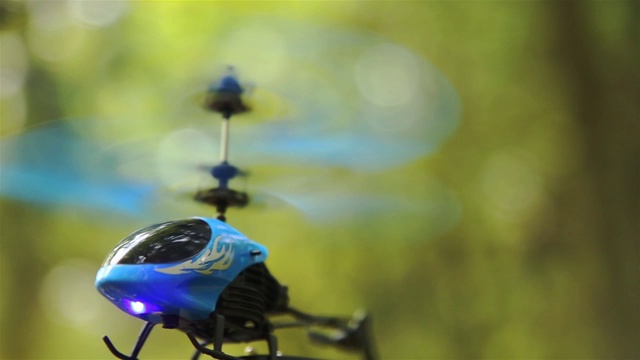 蓝色RC直升机盘旋在森林公园地区的空中高清视频下载
