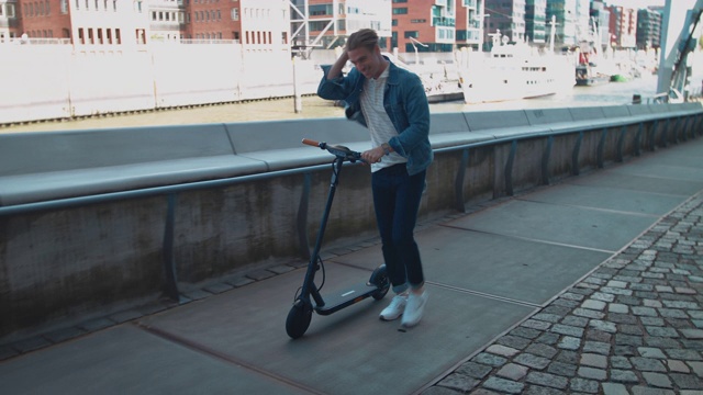 男性在人行道上推电动滑板车视频素材