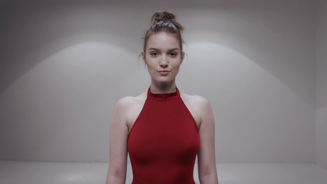 一个穿着红色裙子的芭蕾舞女演员正在工作室里摆姿势视频素材