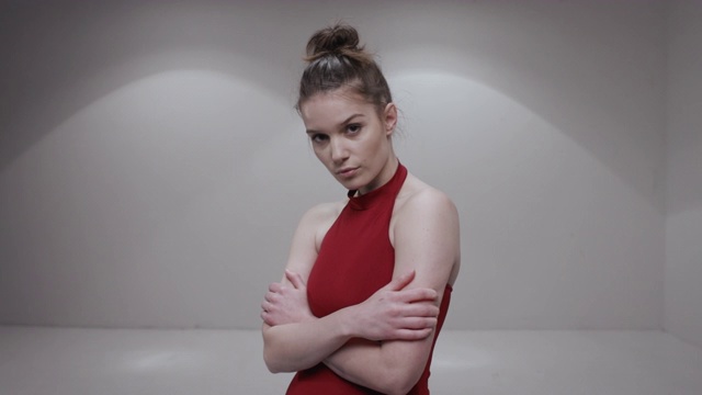 一个穿着红色裙子的芭蕾舞女演员正在工作室里摆姿势视频素材