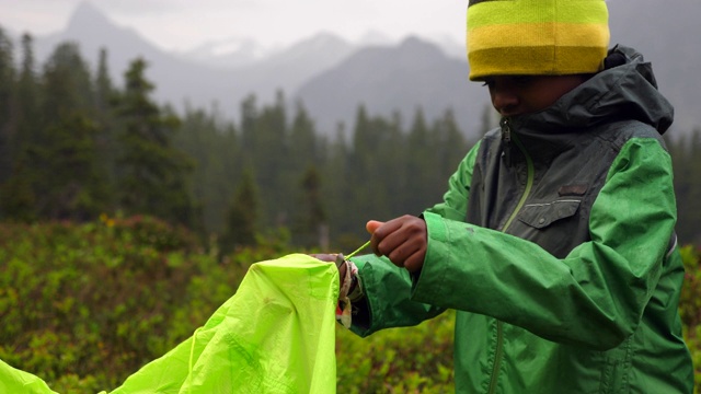 一个小男孩在背包旅行中帮助搭建帐篷视频下载