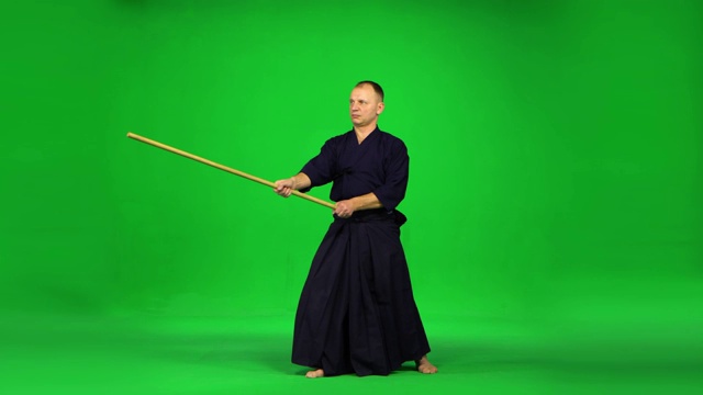 刚毅的剑道武士在绿屏上用竹棍练习武术视频下载