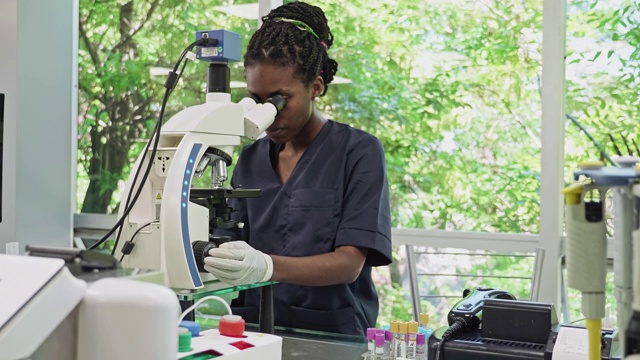 非裔美国女性病理学家在医学实验室中使用显微镜视频下载