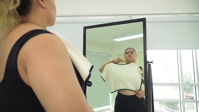 有体重问题的女人对着镜子看自己的身体视频素材