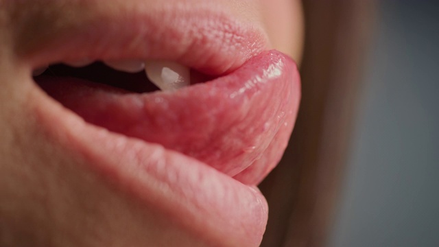 近四分之三微距镜头的嘴与完美的白牙齿。女性以性感的方式舔丰满的嘴唇。女人美丽自然健康的红唇和牙齿与漂亮的微笑。视频下载
