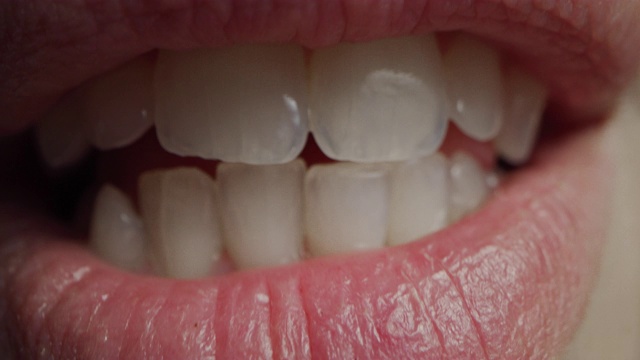近距离微距拍摄的嘴巴与完美的白牙齿。人说话，我们看到嘴和舌头的运动。女性与美丽自然健康的红唇，甚至牙齿与漂亮的微笑。视频素材