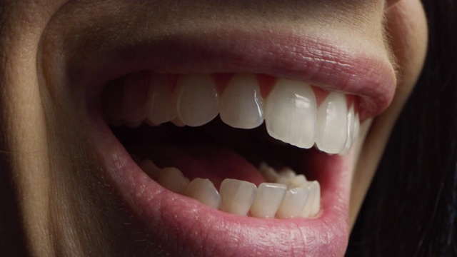 近四分之三微距镜头的嘴与完美的白牙齿。人说话，我们看到嘴和舌头的运动。女人美丽自然健康的红唇和牙齿与漂亮的微笑。视频素材