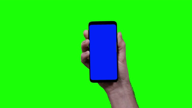 男人的手握智能手机与蓝色croma键和绿色屏幕在背景双swipe到左边两次视频素材