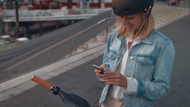 女人用手机解锁推滑板车视频素材