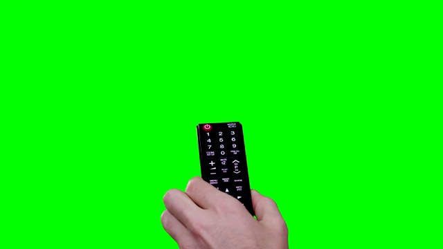 一名男子手持遥控器打开声音，并在绿幕背景下切换频道视频素材