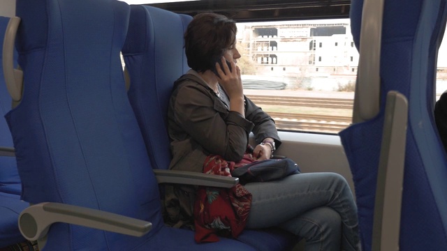 一个女人坐在火车上，一边打电话一边聊天视频素材