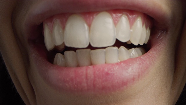 近距离微距拍摄的嘴巴与完美的白牙齿。人说话，我们看到嘴和舌头的运动。女性与美丽自然健康的红唇，甚至牙齿与漂亮的微笑。视频素材