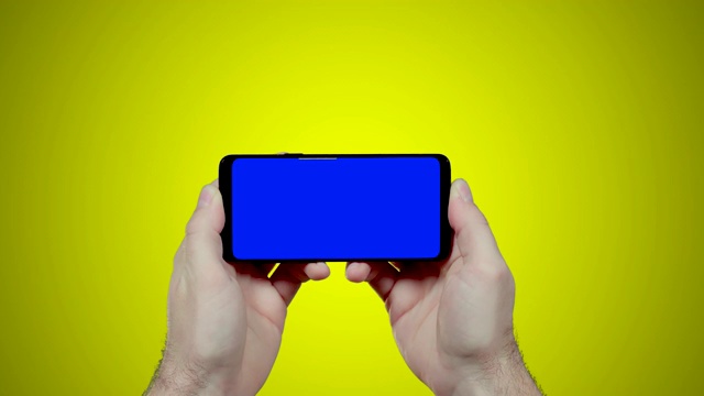 男人的手拿着智能手机水平与蓝色croma键在黄色背景视频素材