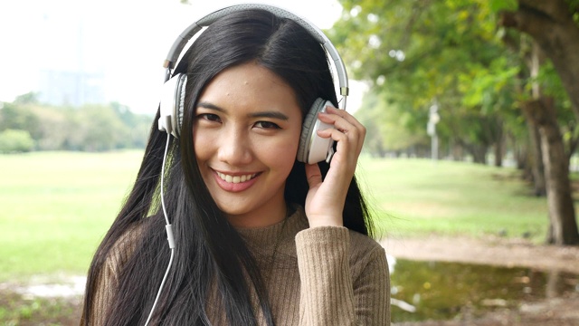 快乐的亚洲女人通过耳机听手机音乐视频素材