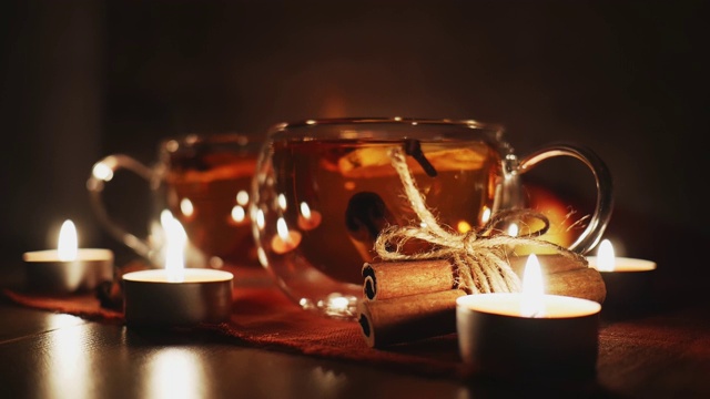 蜡烛周围的苹果酒，果汁，潘趣酒，香料茶，肉桂棒，茴芹和新鲜的苹果在一个木制的背景。冬天晚上喝热饮。季节性热饮料视频素材