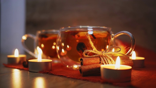 点燃蜡烛周围的苹果酒，果汁，潘趣酒，香料茶，肉桂棒茴芹和新鲜的苹果在一个木制的背景。冬天晚上的热饮。季节性热饮料视频素材