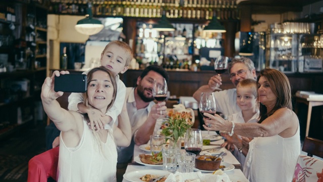 一个多代拉美家庭在餐厅聚餐时的集体自拍视频素材
