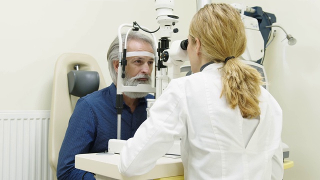 一个留着胡子的老人在眼科诊所接受视力检查视频素材