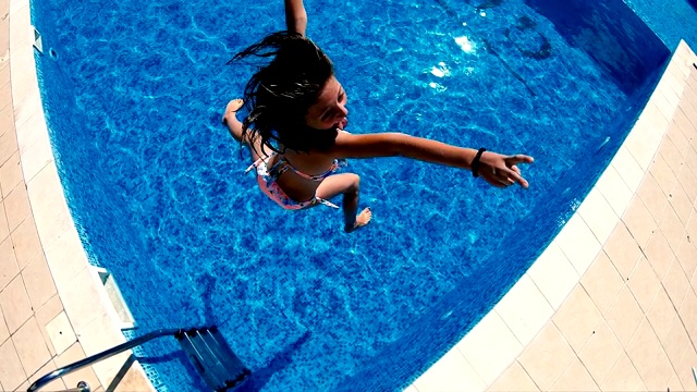 快乐的小女孩在游泳池里跳得很开心，慢镜头视频下载