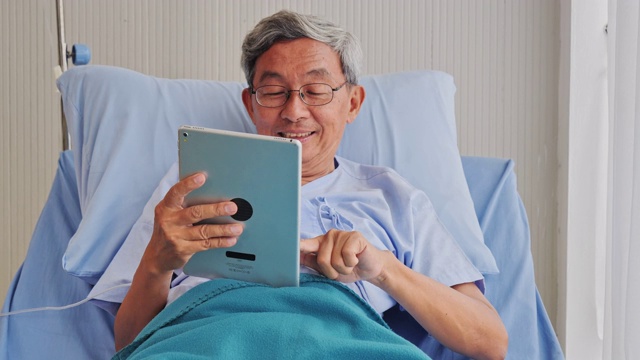 病人上了年纪的亚洲男子使用平板电脑享受他们在医院治疗期间。视频素材